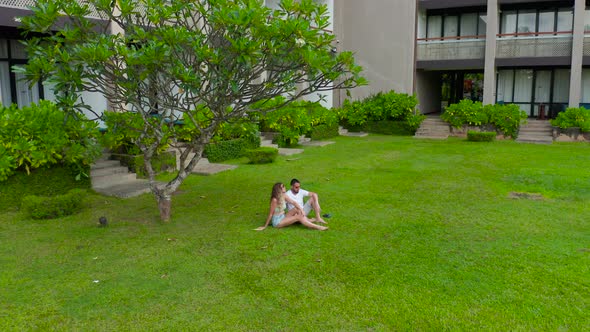 Couple Man and Woman Seat on the Grass Against the Trees in the Tropics Resort in SriLanka
