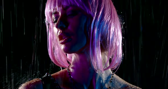 Alluring Young Woman with Pink Wig Is Standing Under Water Flows in Darkness, Closeup Portrait