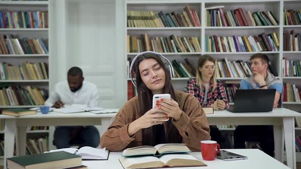 Woman with Long Hair in Headphones Listening Music in the Library