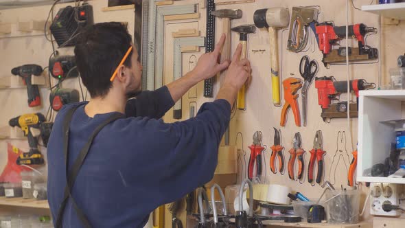 Young Carpenter in Uniform on Background of Stand with Tools