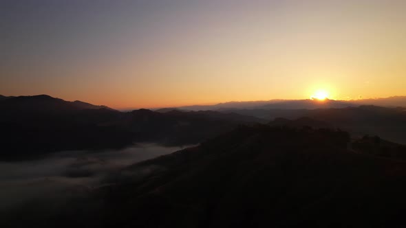 4K Flying through the clouds above mountain tops. Tropical forest with smoke and fog.