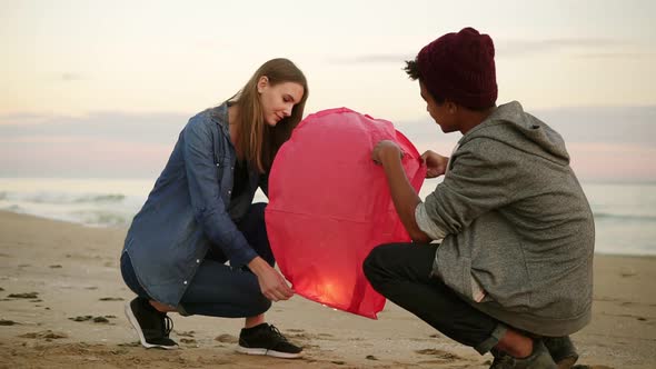 Romantic Date at the Beach During Sunset Young Multiethnic Couple Holding Red Paper Lantern Before