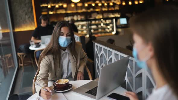 Two Pretty Women Wearing Medical Face Mask Using Laptop to Work