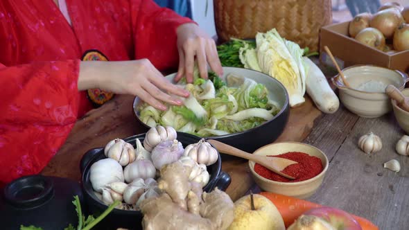 Asian women wearing Korean traditional costumes (hanbok) are Sprinkling salt by hand and Kimchi ingr