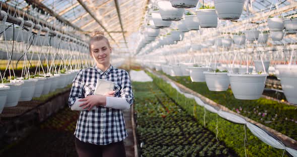 Gardener Using Digital Tablet at Greenhouse and Smile