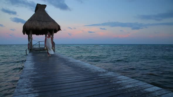 Woman walks down pier at tropical resort