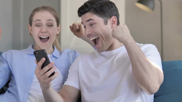 Cheering Excited Couple Using Smartphone