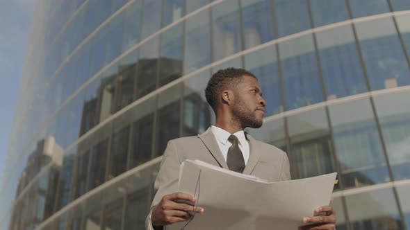 African Man Reading Documents and Looking Around