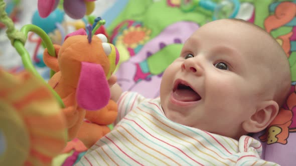 Close Up of Little Boy Face. Portrait of Happy Baby on Colorful Mat with Toys