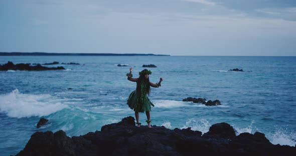Woman performing traditional Hawaiian hula by the ocean alt