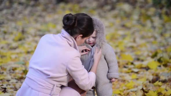 woman wraps her baby outdoors on a cool evening in the park