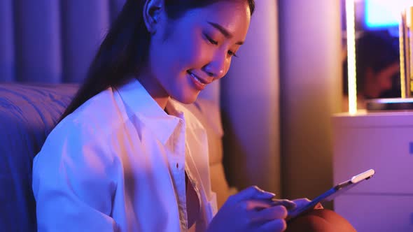 Young Asian beautiful woman enjoy using smartphone in bedroom at night time.