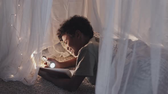 Boy Reading in Pillow Fort