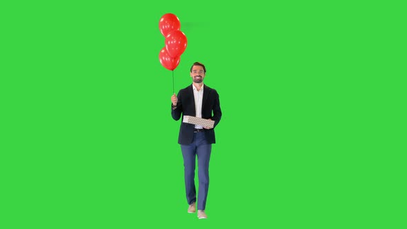 Handsome Guy in an Elegant Suit with a Gift Box and Balloons Walking on a Green Screen Chroma Key