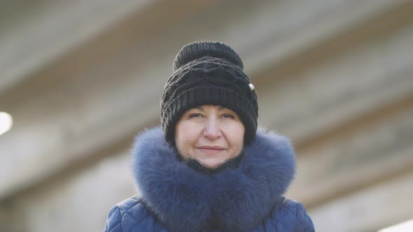 close-up Beautiful caucasian woman in a black stylish hat with a blue fur collar smiles and looks at