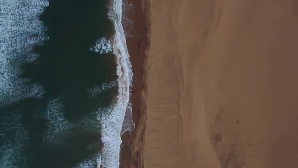 Birds eye drone shot of Sandwich Harbour in Namibia - drone is following the coastline where desert