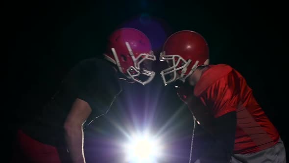 Two Male Footballer Face Their Protective Helmets. Black Background. Slow Motion