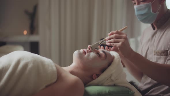 Relaxed Woman Lying on Spa Bed for Facial and Head Massage Spa Treatment By Massage Therapist in a