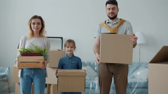 Portrait of Parents and Cute Child Holding Boxes Looking at Camera with Happy Faces During