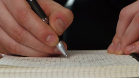 Hand Writing a Message in the Open Notebook.