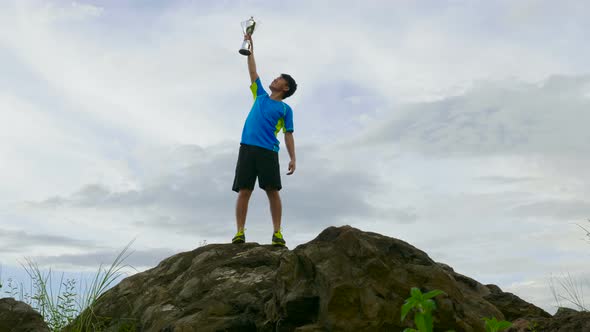 Athlete Celebrating On The Top Of Mountain With Trophy