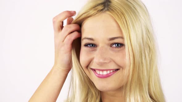 A Young Attractive Woman Turns To the Camera and Smiles, Playing with Her Hair - White Screen Studio