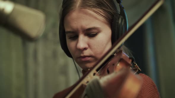 Volinist Rehearsing the Instrumental Melody with Headphones at Microphone