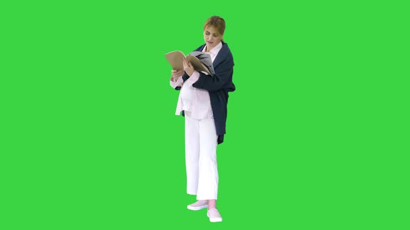 Pregnant Blonde Woman Reading a Book on a Green Screen, Chroma Key