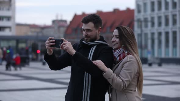 young couple takes a selfie on a city street