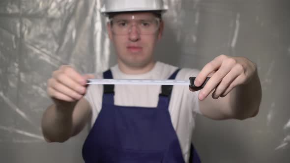 Builder in Blue Overalls and White Hard Hat Helmet and Glasses with Tapemeasure