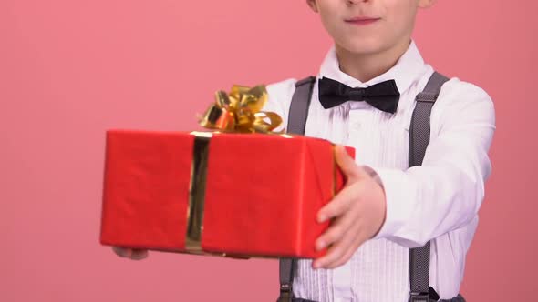 Boy in Suit Showing Gift Box to Camera Celebration and Congratulations Holiday