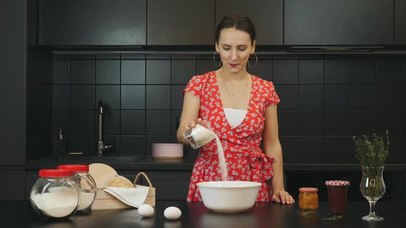 Woman adding sugar to dough and preparing homemade baked cake in professional kitchen. Food concept