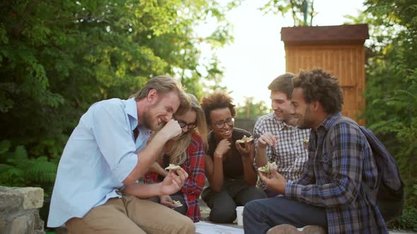 Five Interracial Friends Actively Speaking Laughing Smiling Eating Pizza in Park in Slowmotion