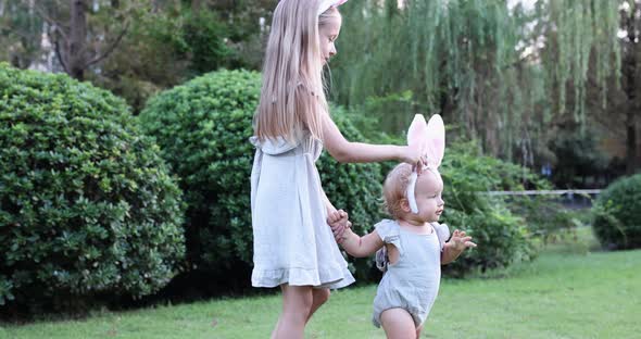 Two Children Wearing Bunny Ears When Pick Up Painted Easter Egg Hunt In Garden or Park