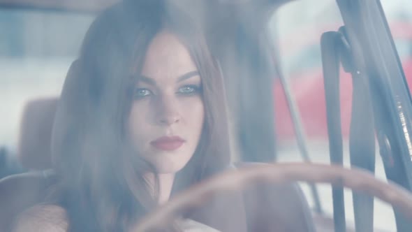 A Feminine Lady with Makeup Sits Behind the Wheel of a Car She Looks Elegant
