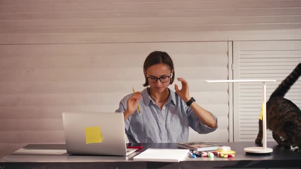 Woman Writing Notes Talking on Cellphone Remote Work From Home Office During Covid Lockdown