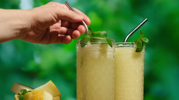 Female Hand Stirs a Straw in a Glass of Cocktail