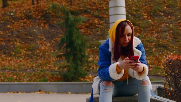 Young Woman with Mobile Phone in City Park