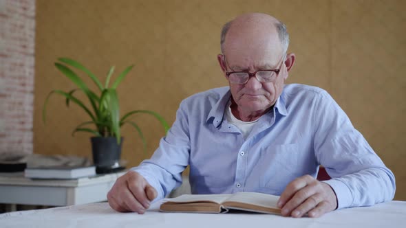 Care for Elderly, Elderly Man with Glasses for Sight Loving Grandson Brings Water While Reading Book