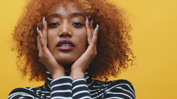 Young African American Black Woman with Curly Afro Hair and Long Nails Posing in Front of Yellow