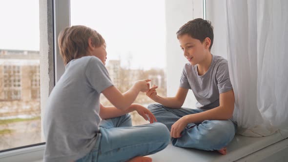 Friends Play to Rock Paper Scissors Game on Window Sill