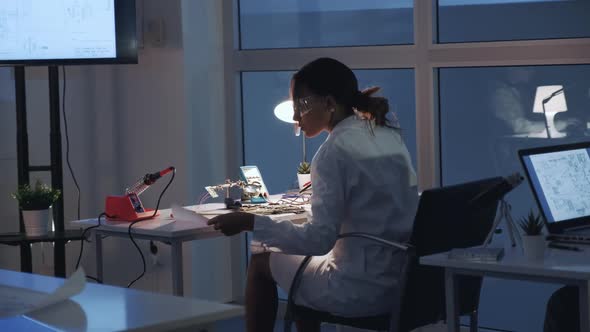 Back View of Female Electronics Engineer Checking Motherboard with Multimeter Tester