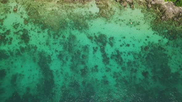 Flying Over a Rocky Coastline with Crystal Clear Turquoise Blue Water.