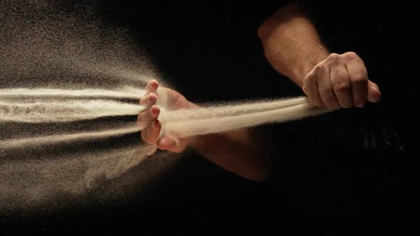 Stream of Dry Sand Pours Into Palm of Man and is Spilling Through His Fingers on Black Background