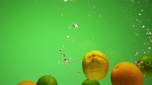 Citrus Fruits Falling in Water with Bubbles Green Background in Slow Motion  Orange Lime Lemon