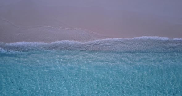 Wide angle overhead abstract shot of a sandy white paradise beach and aqua blue ocean background in 