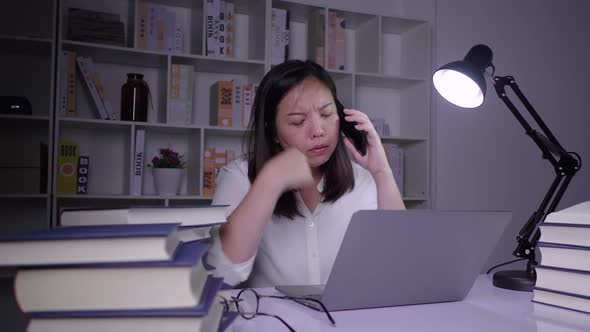 Stressed Asian woman working hard  on laptop  and thinking about problem in a room at night