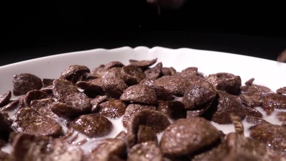 Morning Breakfast Milk Is Poured Into Chocolate Cocoa Flakes in a White