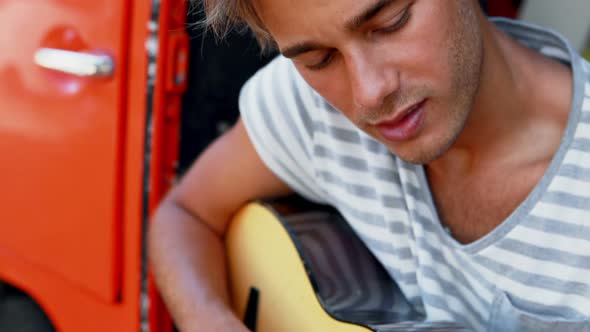 Man playing guitar in camper van 4k