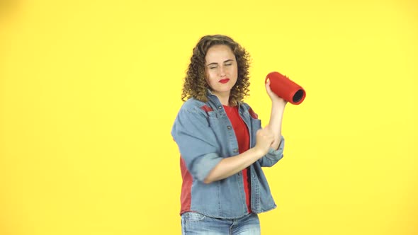 Girl Listening To Music with Bluetooth Portable Speaker and Dancing on Yellow Background at Studio.